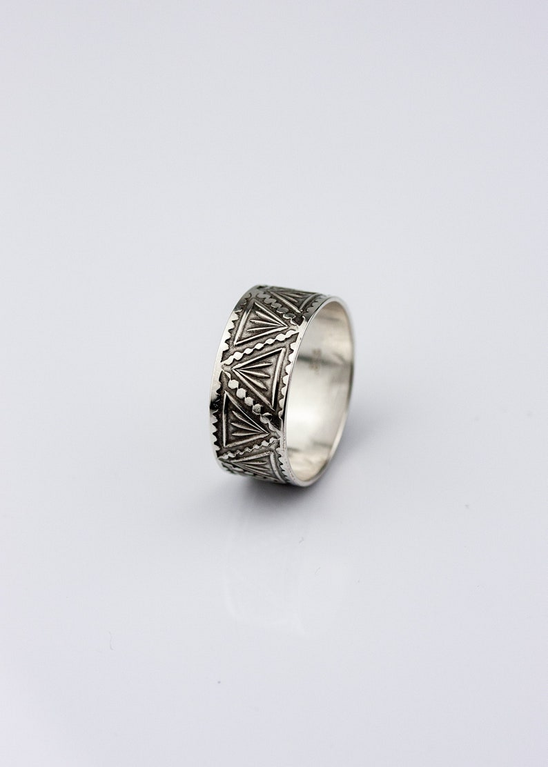 May include: A silver ring with a geometric pattern around the band.