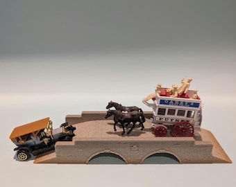May include: A miniature diorama featuring a stone-colored bridge with two arches. On the bridge, two dark brown horses pull a white and red double-decker bus with OAKEY'S KNIFE POLISH and PUTNEY text. A vintage car with a tan roof sits at the base.