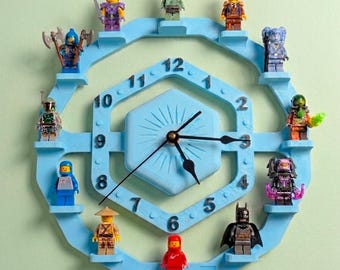 May include: A light blue wall clock with a hexagonal center and a circular outer frame featuring twelve small shelves. Each shelf holds a unique plastic minifigure character. The clock face displays black numbers from 1 to 12 and black hands.
