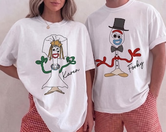 May include: Two white crewneck t-shirts featuring cartoon character graphics. The left shirt displays a character in a wedding veil and dress with the name Karen. The right shirt shows a character in a top hat and bowtie with the name Forky.