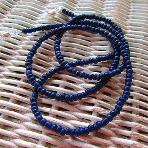 May include: A dark blue beaded eyeglass chain with gold-toned metal clasps. The chain is made of small, round beads and is designed to hold eyeglasses securely around the neck.