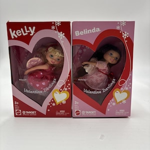May include: Two boxed Valentine Darlings dolls, "Kelly" and "Belinda." Each doll is in a heart-shaped box with the words "Valentine Darlings" and "Target Special Edition." The Kelly doll has blonde hair and a pink dress, while Belinda has dark hair and a pink dress.