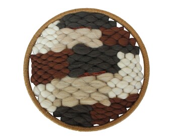 May include: A circular wall hanging with a woven design in shades of brown, gray, and white. The woven design is framed by a natural wood hoop.