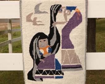 May include: A woven wall hanging with a fringe border features a colorful design of two figures in purple, blue, and black against a white background.