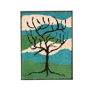 May include: A framed needlepoint wall hanging with a black tree silhouette against a background of green, blue, and white abstract shapes.