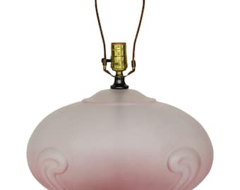 May include: A pink frosted glass table lamp with a black base and a brass lampshade holder.