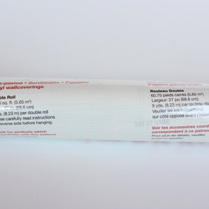 May include: A white tube of pre-pasted, scrubbable, peelable vinyl wallcovering. The label states that the double roll is 60.75 square feet (5.65 square meters) and 9 yards (8.23 meters) per roll. It also includes instructions to read the reverse side before hanging.