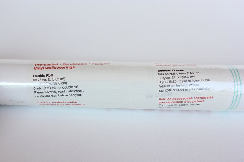 May include: A white tube of pre-pasted, scrubbable, peelable vinyl wallcovering. The label states that the double roll is 60.75 square feet (5.65 square meters) and 9 yards (8.23 meters) per roll. It also includes instructions to read the reverse side before hanging.