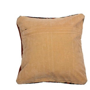 May include: A beige pillow with a red and black patterned back. The pillow is made of a soft, plush fabric.