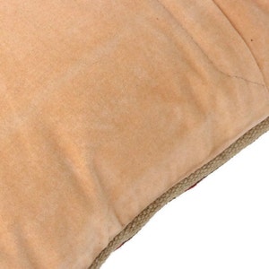 May include: A tan-colored throw pillow with a jute trim. The pillow is made of a soft, plush fabric.