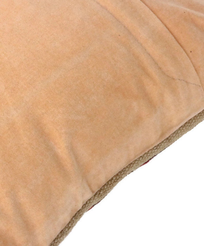 May include: A tan-colored throw pillow with a jute trim. The pillow is made of a soft, plush fabric.