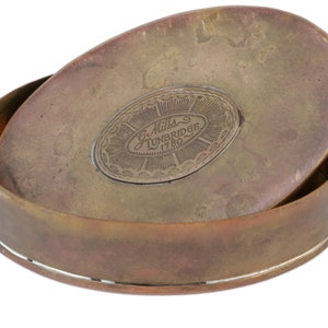 May include: An oval-shaped brass box with a hinged lid. The lid has an engraved inscription that reads "G. Mills Tunbridge 1780."
