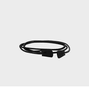 May include: A thin black cord belt featuring a smooth, rounded texture and two matching black, flat, tapered end pieces. The cord is coiled into multiple overlapping loops, creating a circular shape with the ends positioned side by side.