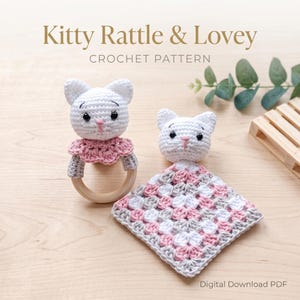 May include: A crochet pattern for a Kitty Rattle & Lovey. The image shows a white cat-shaped rattle with a pink and gray collar and a wooden ring, and a matching lovey blanket in white, pink, and gray. The text "Kitty Rattle & Lovey Crochet Pattern" is at the top.