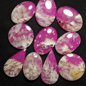 May include: Ten pink and white agate cabochons with a cloudy pattern. The cabochons are oval and teardrop shaped.