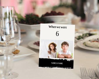 May include: A black and white table number card with a black and white photo of two children. The card says "When we were 6" and "NAME & NAME".