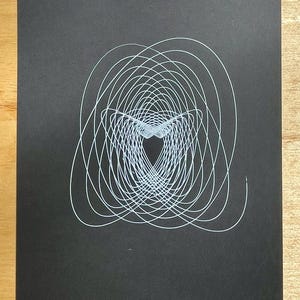 Puede incluir: Una impresión de arte abstracto en blanco y negro con un diseño geométrico de círculos superpuestos que crean una forma de corazón en el centro.