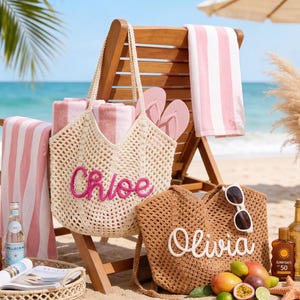 May include: A beach scene with a wooden chair, striped pink towels, and two crochet tote bags. One bag is beige with "Chloe" in pink, the other is brown with "Olivia" in white. Accessories include sunglasses, flip-flops, and a tray with drinks and fruit.