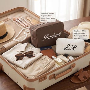 May include: An open suitcase containing a large brown textured bag with the white text Rachael, a small white textured bag with the black text LR, two straw hats, a beige shirt, beige shorts, sunglasses, a passport holder, and toiletries.