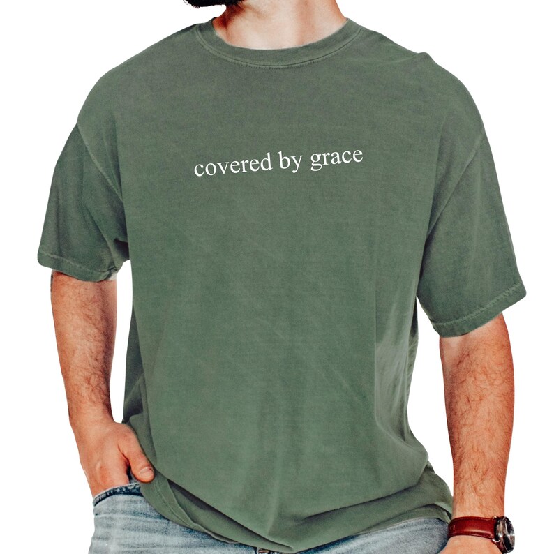 a man wearing a green shirt that says covered by grace