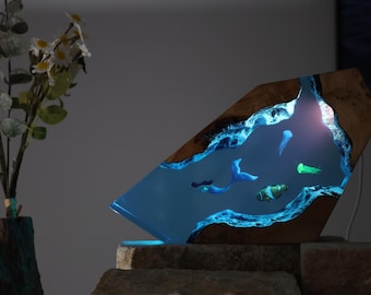 Könnte beinhalten: Handgefertigte Harzlampe mit einer Unterwasserszene mit Fischen und Quallen. Die Lampe hat einen Holzrahmen und einen blauen Harzinnenraum, der einen Leuchteffekt erzeugt. Die Lampe ist etwa 30 cm hoch.