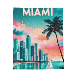 May include: A Miami-themed blanket featuring a colorful illustration of the city skyline, a palm tree, and a sailboat on the water. The word "MIAMI" is displayed across the top in pink and white letters. The background features a sunset with pink and blue hues.