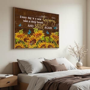 May include: A framed wall art piece with a wooden background. The art features a row of sunflowers, blue butterflies, and the text "Every day is a new beginning, take a deep breath and start again."