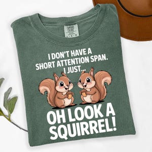 May include: Green Comfort Colors t-shirt with the text "I DON'T HAVE A SHORT ATTENTION SPAN. I JUST... OH LOOK A SQUIRREL!" and a cartoon of two squirrels holding acorns. The shirt is a solid green color.