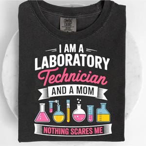 May include: Black t-shirt with the text "I AM A LABORATORY Technician AND A MOM NOTHING SCARES ME" in white and pink. The shirt features illustrations of laboratory glassware in pink, yellow, and blue.