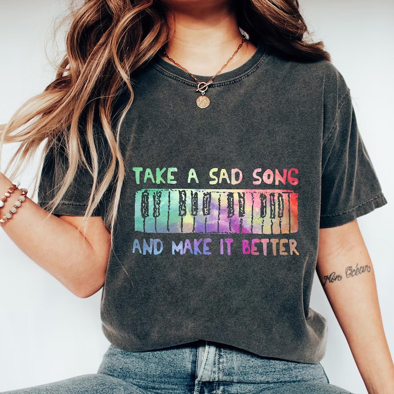 A person wearing a black t-shirt with a colorful graphic design and text printed on it.