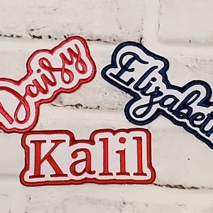 May include: Three embroidered patches with names "Daisy", "Elizabeth", and "Kalil". The patches are white with red and blue outlines.