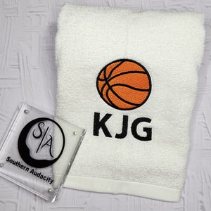 May include: White towel with an orange basketball and the name KJG embroidered in black.