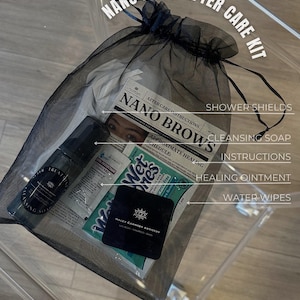 Op de afbeelding: Een zwarte mesh tas gevuld met nazorgproducten voor microblading van wenkbrauwen. De producten omvatten reinigende zeep, helende zalf, vochtige doekjes en doucheschilden. De tas bevat ook een pamflet met instructies en een genezingsschema.