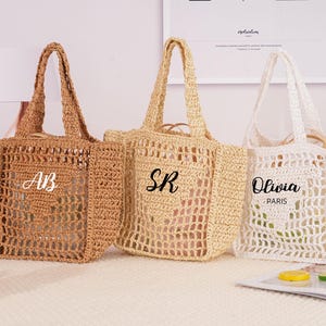 Op de afbeelding: Drie geweven draagtassen in bruin- en wittinten. De tassen hebben open weefpatronen en stevige handvatten. Elke tas heeft een gepersonaliseerde naam of initialen: "AB", "SR" en "Olivia, Paris".