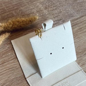 May include: A gold ring with a simple design is displayed on a white velvet ring box. The box is closed and has the text "STILECHT COLOGNE" printed on the bottom.