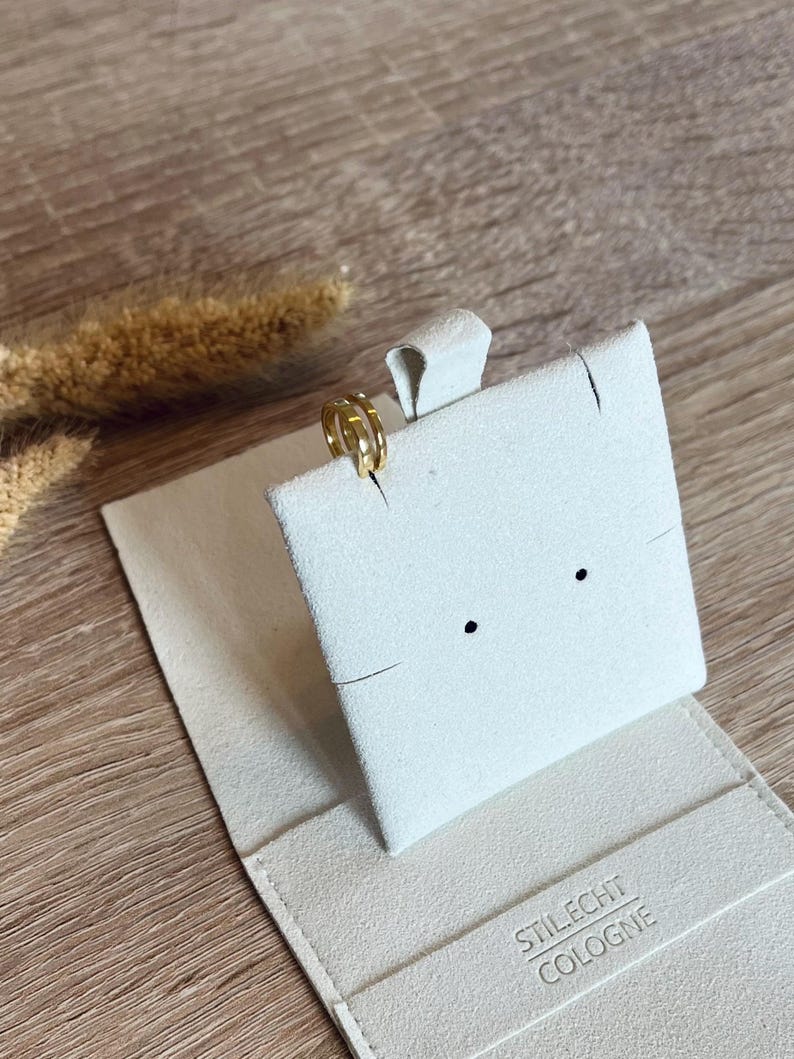 May include: A gold ring with a simple design is displayed on a white velvet ring box. The box is closed and has the text "STILECHT COLOGNE" printed on the bottom.