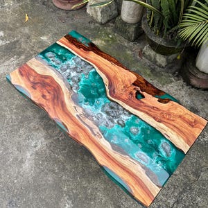 May include: A wooden coffee table with a green epoxy river running through the centre. The epoxy has a white glitter finish.