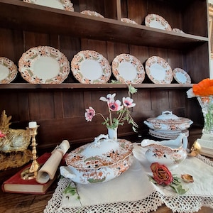 Large antique Crown Derby Imari china set displayed on an oak Welsh dresser featuring dinner plates, side plates, covered tureens, gravy boat, brass serving spoon and fresh garden flowers in a traditional English dining room setting.