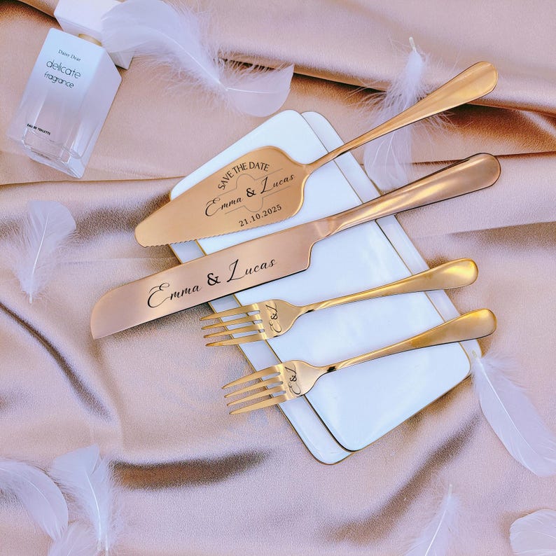 May include: A set of rose gold cake serving utensils including a cake server, a knife, and two forks. The server is engraved with "SAVE THE DATE Emma & Lucas 21.10.2025", the knife with "Emma & Lucas", and both forks with the initials "E & L".