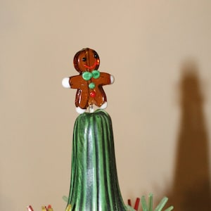 May include: A green ceramic Christmas tree with a gingerbread man topper and colorful plastic star ornaments.