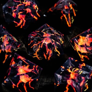Puede incluir: Siete dados poliédricos con un diseño de lava ardiente. Los dados transparentes presentan una base negra y patrones internos vibrantes en naranja y rojo. Los números dorados son visibles en cada dado. Los dados están dispuestos sobre una superficie oscura y texturizada.
