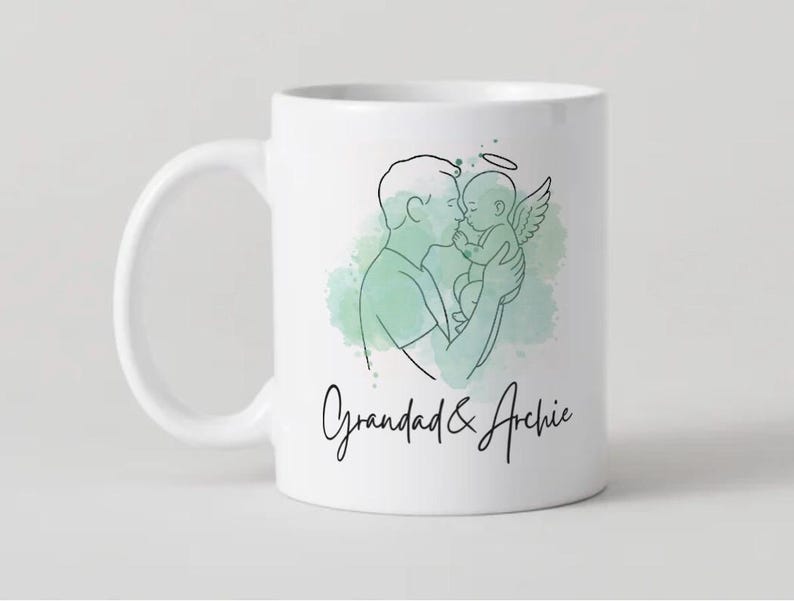 Puede incluir: Taza de cer&aacute;mica blanca con un dibujo lineal de una persona sosteniendo a un beb&eacute; con alas de &aacute;ngel y un halo. La taza tiene el texto "Grandad & Archie" en una fuente manuscrita, con un lavado de acuarela verde en el fondo.
