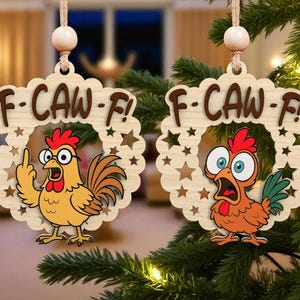 May include: Two wooden Christmas ornaments with a cartoon rooster design. Each ornament has the text "F-CAW-F!" above a rooster illustration. One rooster is giving the middle finger, and the other is shocked.