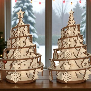 Può includere: Due decorazioni per l'albero di Natale in legno. Ogni albero ha una stella in cima ed è decorato con ornamenti come fiocchi di neve, stelle e omini di pan di zenzero. Gli alberi sono in legno chiaro con accenti marroni.