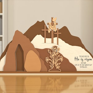 May include: A wooden Easter scene depicting a mountain with three crosses, a tomb, and a floral arrangement. The text "He is risen" is displayed on the base. The color palette includes shades of brown, beige, and cream.
