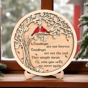 May include: A round wooden plaque with a tree and two red birds. The plaque has the words "Goodbyes are not forever. Goodbyes are not the end. They simply mean I'll miss you until we meet again."