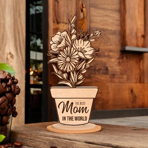 May include: Wooden cutout of a potted flower with the text "The Best Mom in the World" on the pot.