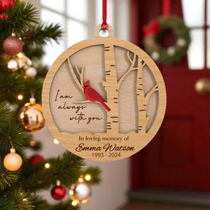May include: Wooden Christmas ornament with a laser-cut design. The ornament features a red cardinal perched on a branch, with the text "I am always with you." Below, it reads "In loving memory of Emma Watson 1993-2024."