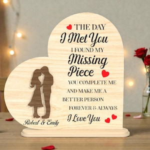 May include: A wooden heart-shaped plaque with a light wood grain finish. The plaque features a silhouette of a couple, the text "The Day I Met You, I Found My Missing Piece, I Love You," and the names "Robert & Emily." Red heart accents are included.