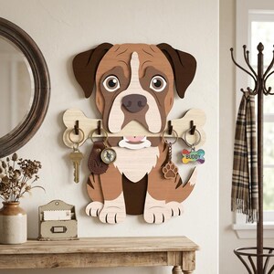 May include: Wooden dog-shaped key holder with a bone-shaped key rack. The dog is brown, white, and tan with a friendly expression. Includes keychains with a compass, paw print, and the name "Buddy".